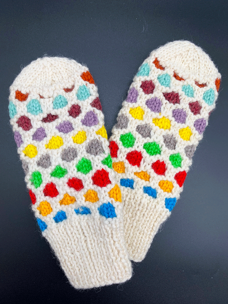 A white pair of knit mittens with colourful circles going around the mittens. Colours consist of blue, orange, red, green, grey, yellow, purple, maroon, light blue, and dark orange. No circles on both ends of the mittens.