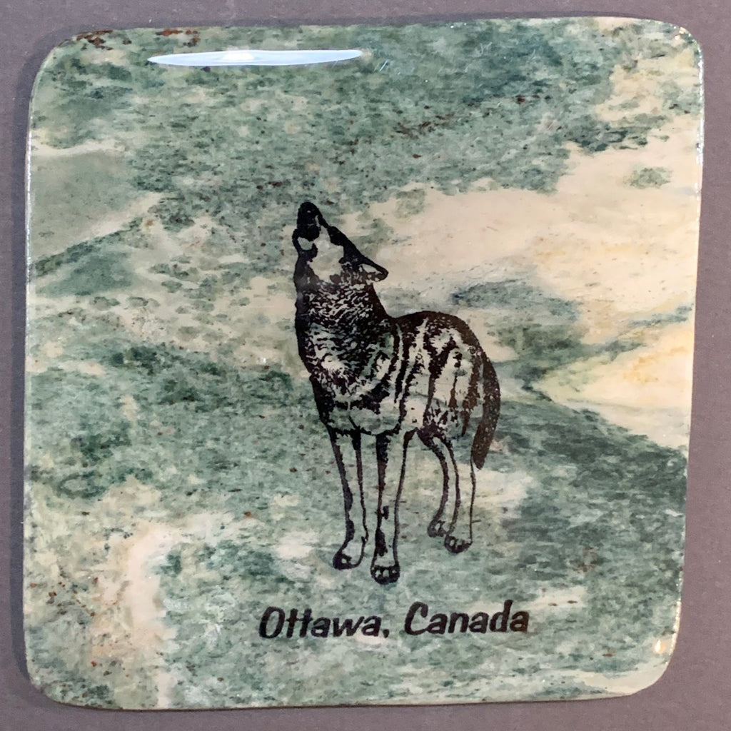 This coaster features the image of a wolf standing while howling into the sky, the words Ottawa, Canada below. The image is on a piece of canadian shield marble with mineral lines running through in unique colours, lines, and patterns. The coaster is finished with a clear coat, giving it a shiny finish.