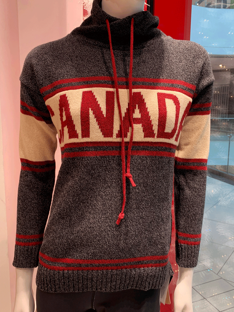 A dark sweater, with sets of two red strips around the cuffs and bottom, upper arms, and upper and lower chest. Canada is written in red on a white strip spanning across the chest. The high neck features red drawstrings.