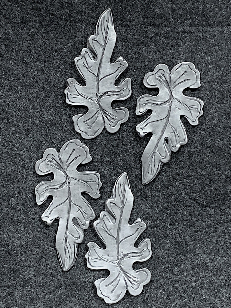 Four pewter magnets in the shape of oak leaves. 