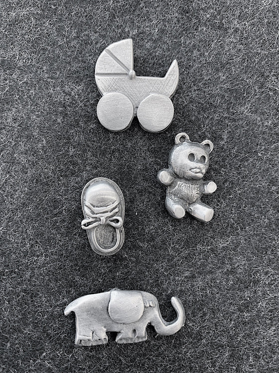 This set of four magnets includes a 1960's style baby carriage, a teddy bear, a baby shoe, and an elephant. 