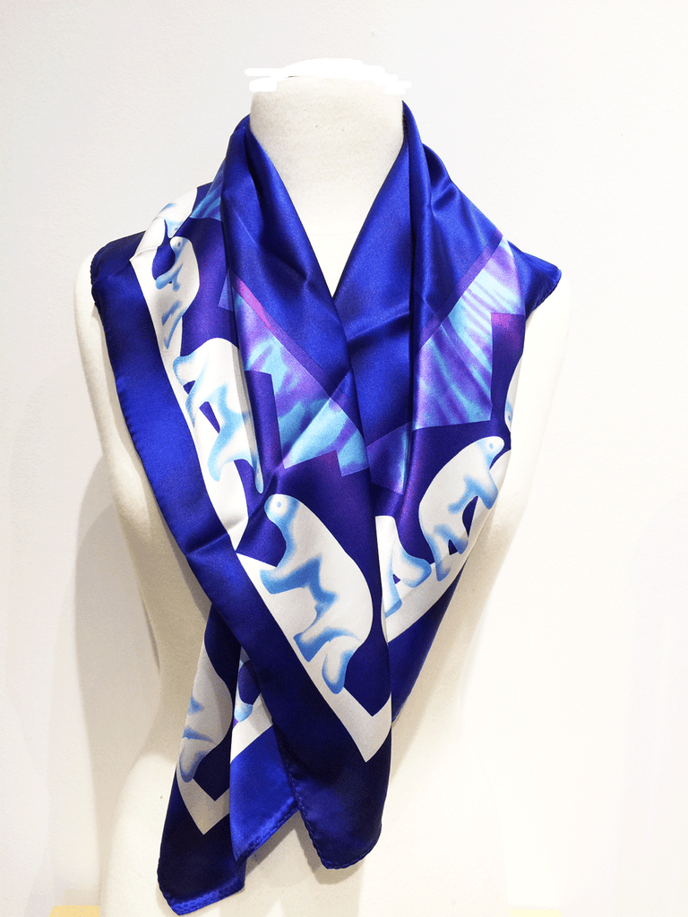 Pictured here is a royal blue silk scarf with light blue and white accents. Featured on the scarf is the majestic Canadian polarbear.