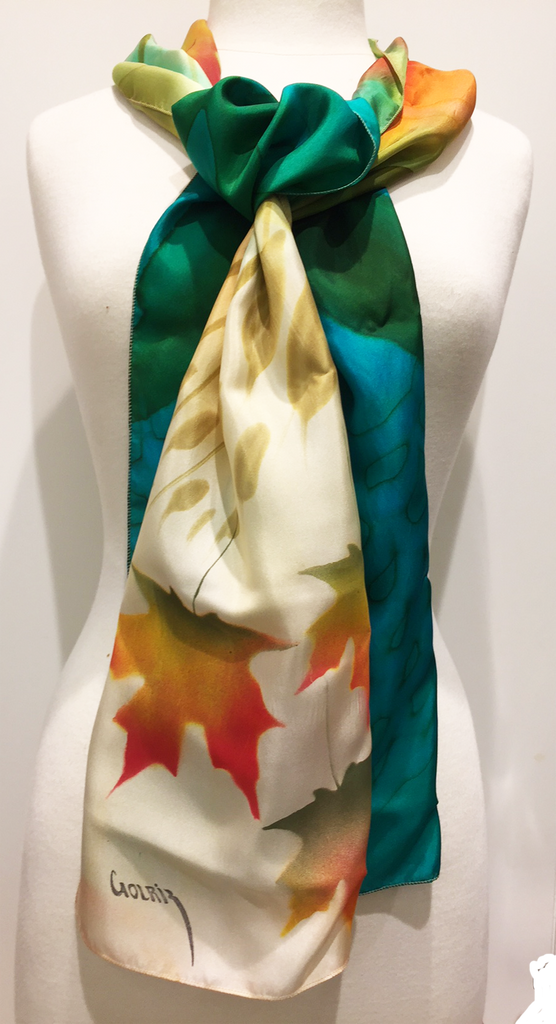 Pictured here is a green/teal/gold/ivory hand-painted silk scarf featuring several Canadian maple leaves of various sizes.