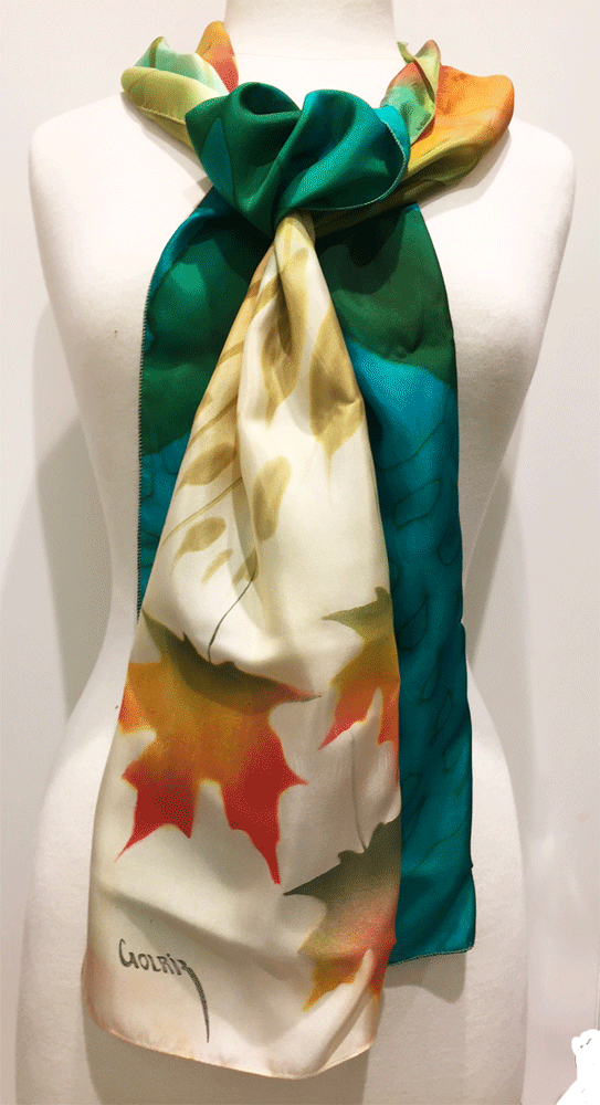 Pictured here is a green/teal/gold/ivory hand-painted silk scarf featuring several Canadian maple leaves of various sizes.