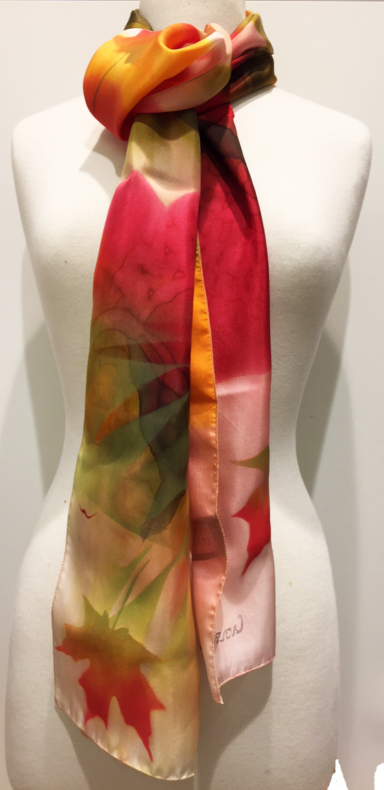 Pictured here is a red/orange/gold/ivory hand-painted silk scarf featuring several Canadian maple leaves of various sizes.