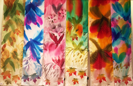 Pictured here is six different hand-painted silk scarves with various colour schemes. Each scarf features several Canadian maple leaves of various sizes.