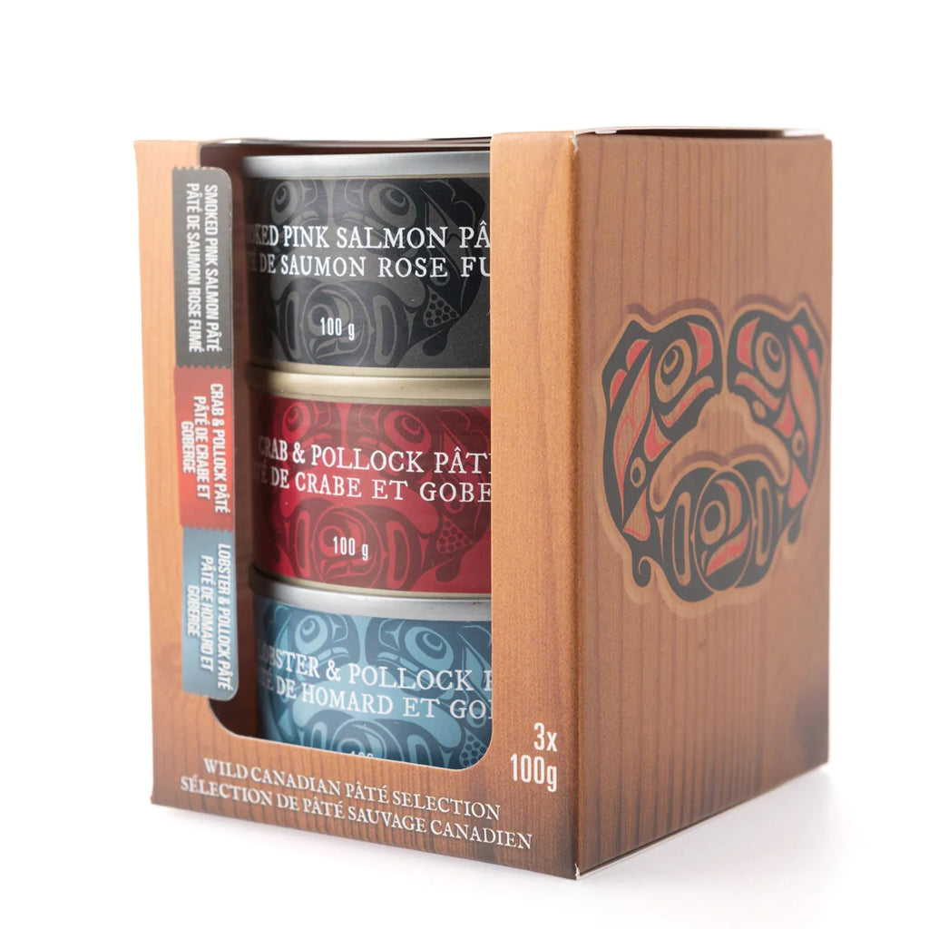 Three tins of 3 different colours. Each colour represents a different seafood pâté. Black is Smoked Pink Salmon Pâté, red is Crab and Pollock Pâté, and blue is Lobster and Pollock pâté. The box features Haida art of the Canadian pacific salmon by artist Don Yeomans.  