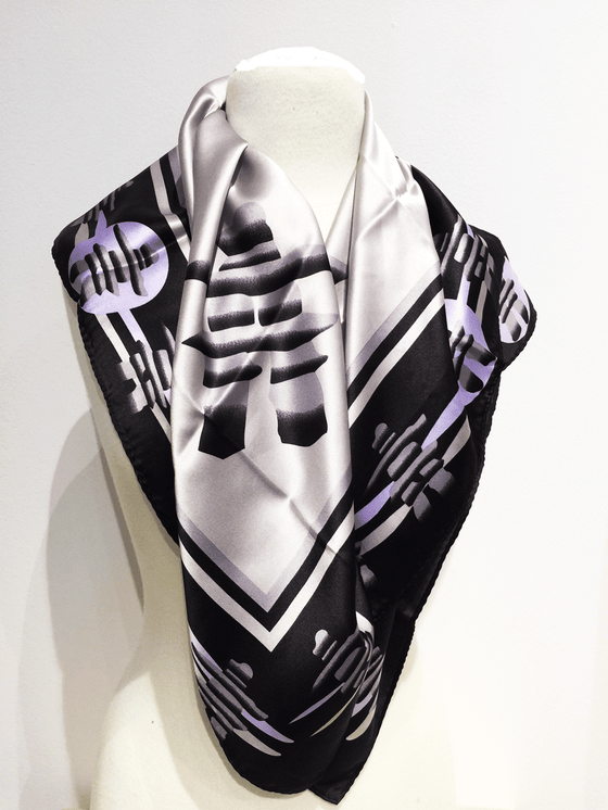 Pictured here is a silver silk scarf with lavender and black accents. Featured on the scarf is the stately Canadian Inukshuk.