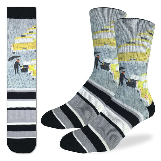 These fun socks feature a man in a suit with a briefcase and holding an umbrella about to enter one of the five yellow taxi cabs lined up one in front of the other. The background of the image is grey, and the image is printed twice on each sockmirriored on the vertical. Below the image white, grey, and black stripes in asymmetrical pattern to the end of the toe. The heel and rim of the sock are black. The active fit socks sport elastic arch bands to contour to your feet and provide support.